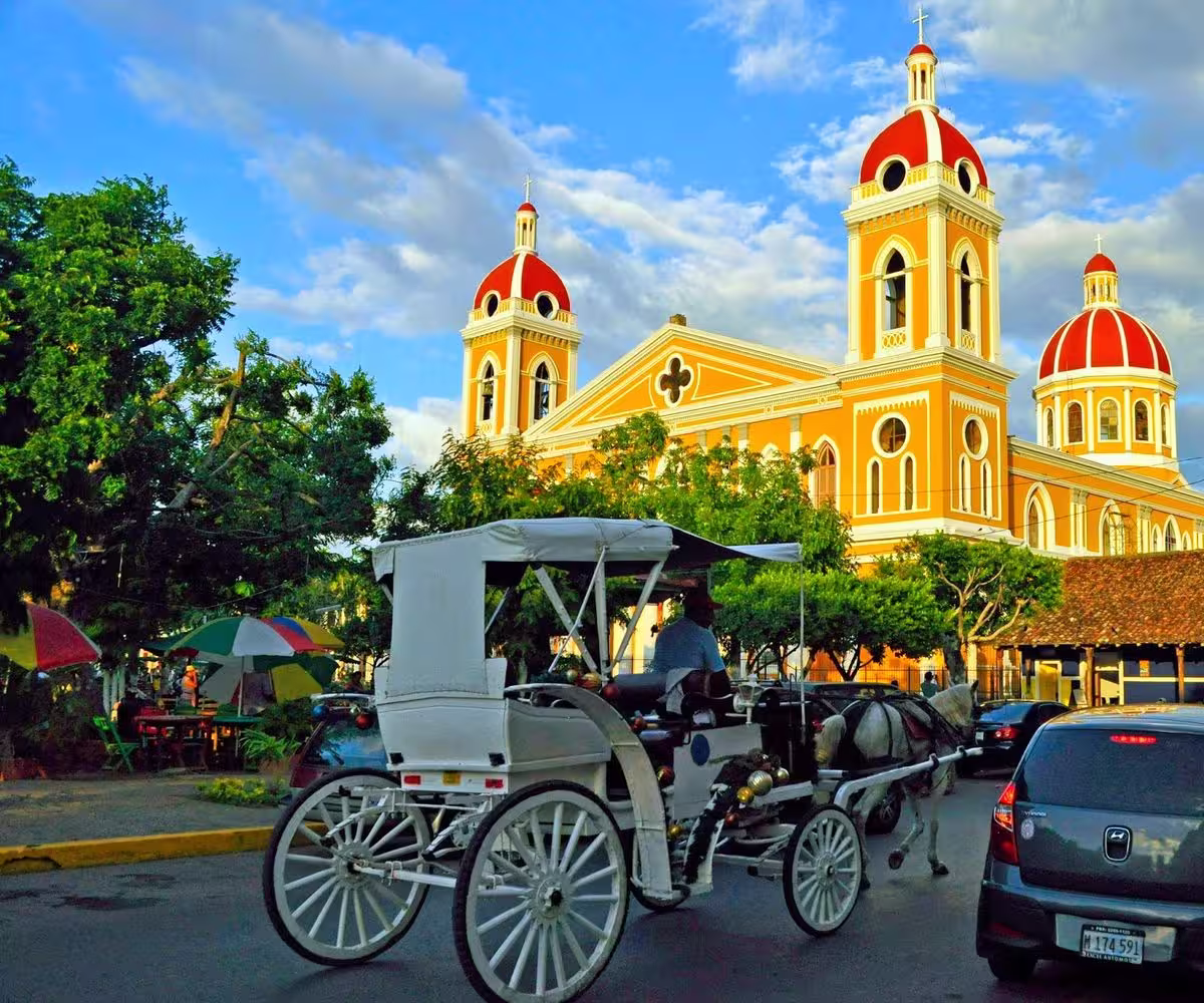 Horse drawn carriage tour past the yellow cathedral in historic colonial Granada Nicaragua