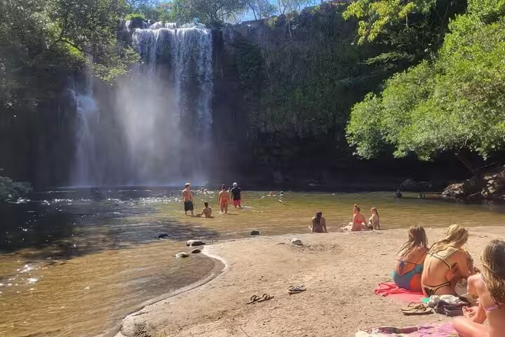 Visitors swimming in natural pool at Llanos del Cortez waterfall in Guanacaste