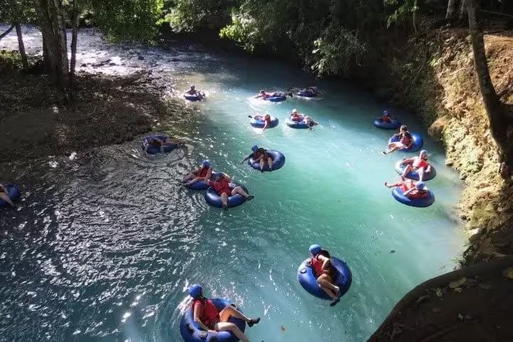 Adventurers river tubing down tropical jungle river rapids near Rio Celeste