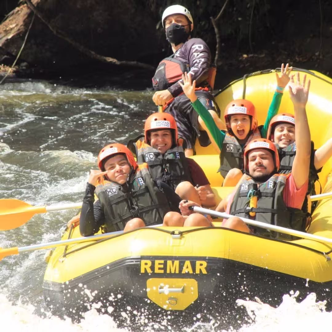 Happy rafting team celebrating with paddle high five after conquering Tenorio River rapids